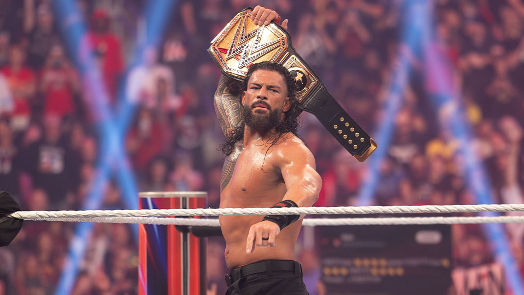 Roman Reigns in the ring holding up a belt