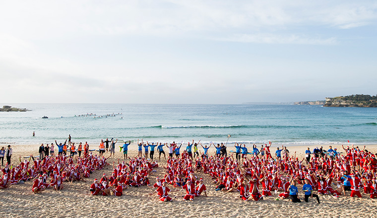 Hundreds of Aussies dress as Santa to take part in largest surfing lesson