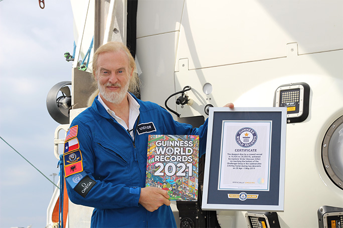 Victor beside the Limiting Factor sub, holding one of his Guinness World Records certificates and the latest book in which he features