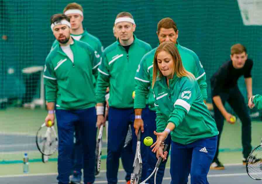 People in green jackets playing tennis