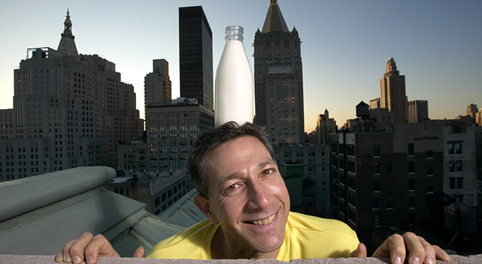 man balancing milk bottle on his head