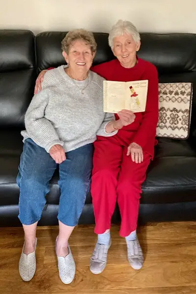 Lynley and Jeanette sitting on the sofa and holding the card