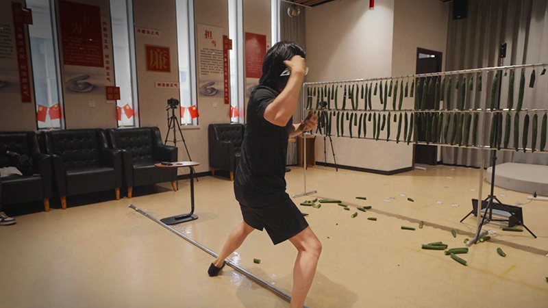 Zhang throwing playing cards at cucumbers