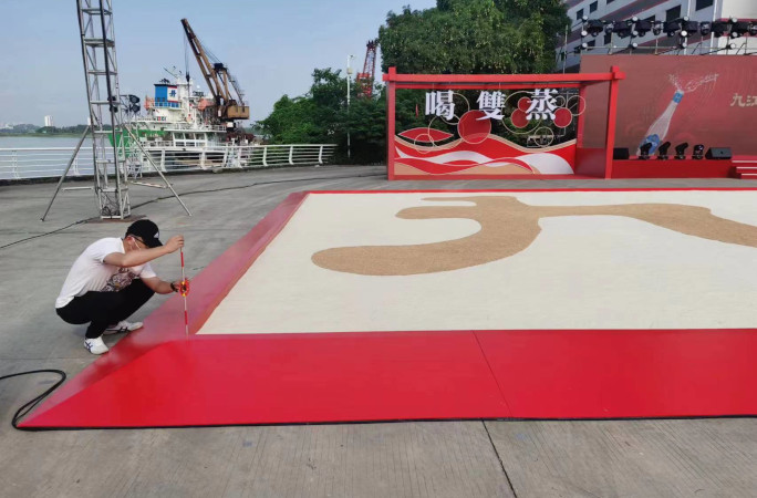 Man measuring the rice on the largest grain mosaic