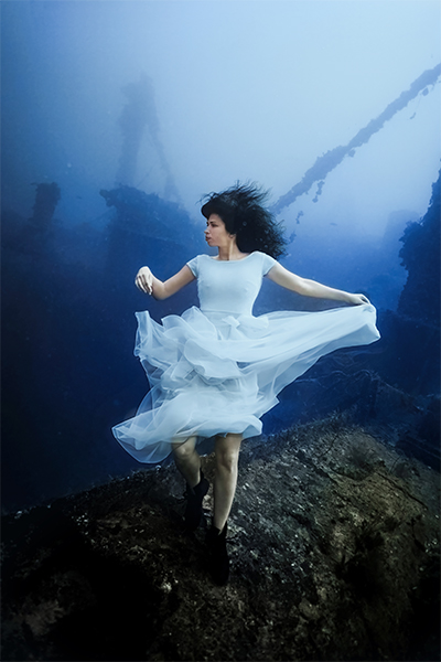 Model posing underwater while holding dress
