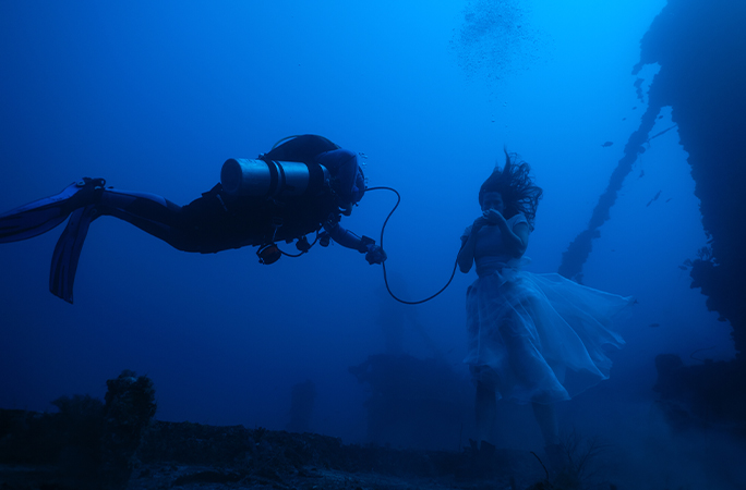 Scuba diver gives model some air underwater