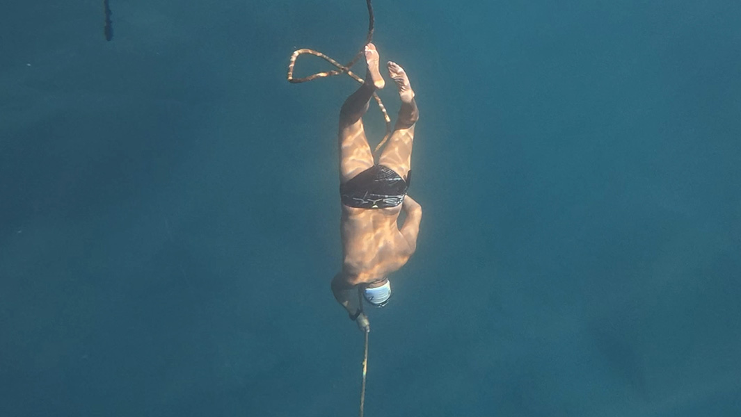 split image of diver sitting on the edge and under the water
