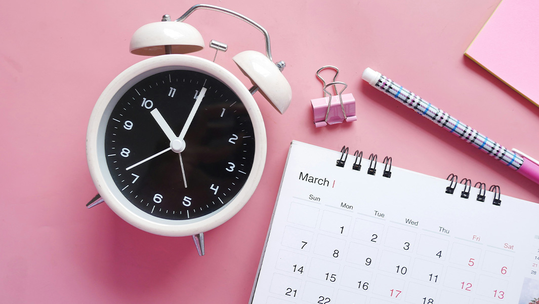 a clock lying on a desk next to a calendar