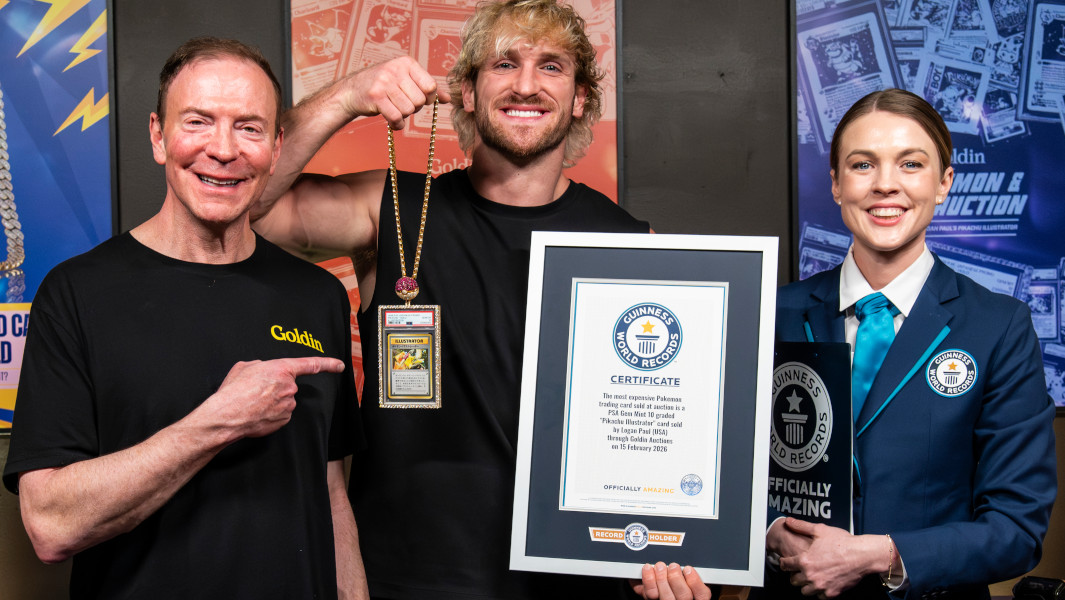 Logan Paul standing next to a Guinness World Records adjudicator and auction house representative holding the Pokemon card and a certificate