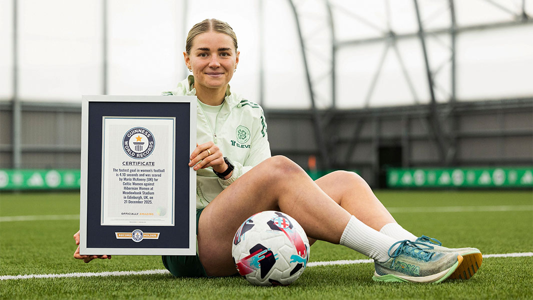 Celtic's Maria McAneny sitting on the pitch with her GWR certificate