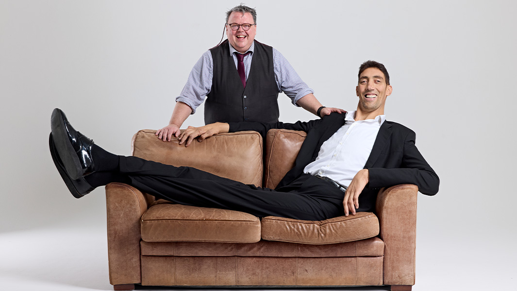 Sultan sitting on a sofa with his legs hanging off the other side with GWR's Craig Glenday stood behind him