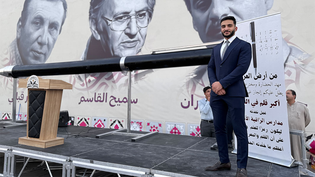 Yahya standing next to the largest ball point pen