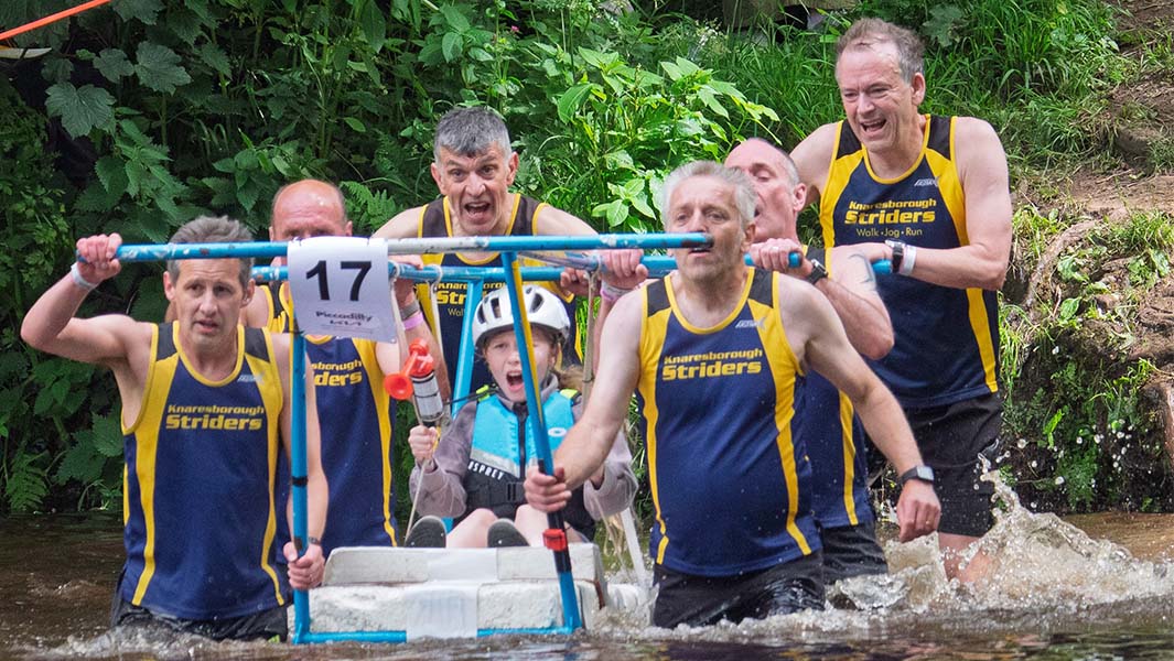 Team taking part in the bed race, walking through the water