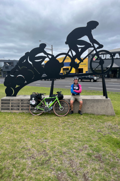 Mark and his bike under a sculpture of a cyclist