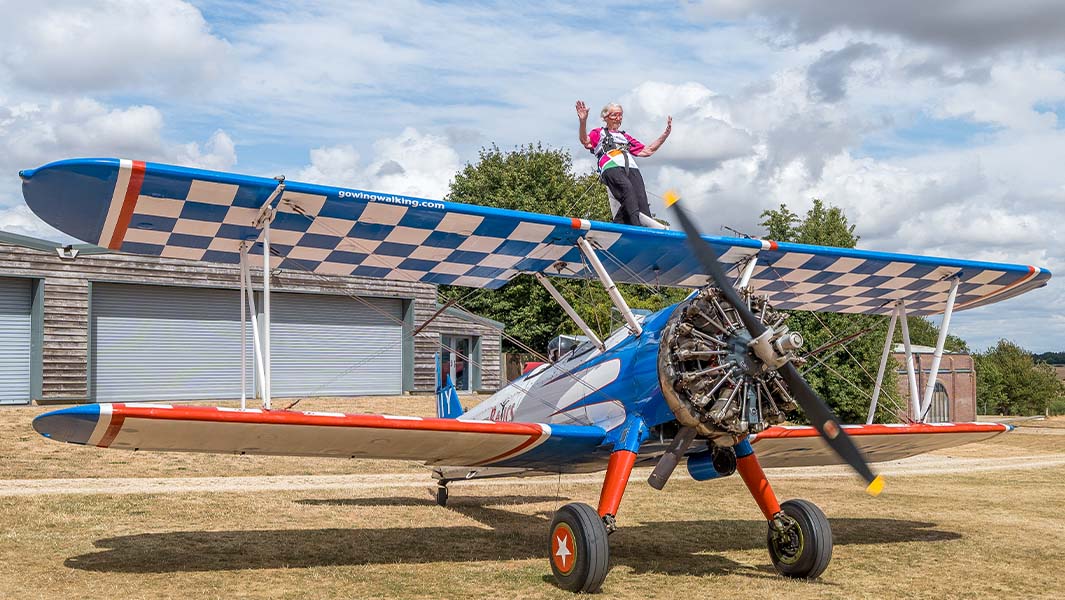 split image of Betty sitting on top of the plane and during her wing walk