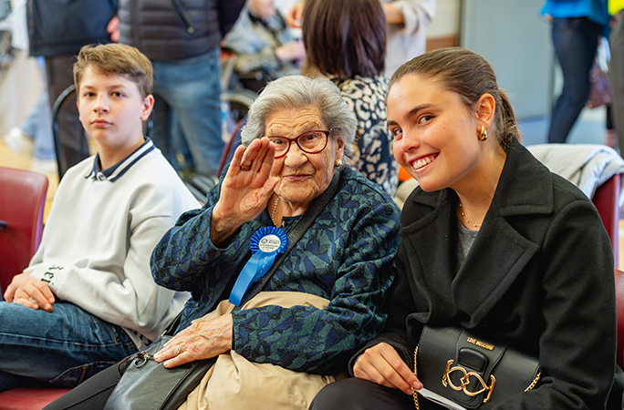 a female centenarian sat next to her family