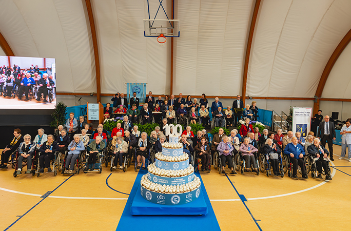 largest gathering of centenarians sit in front of a cake