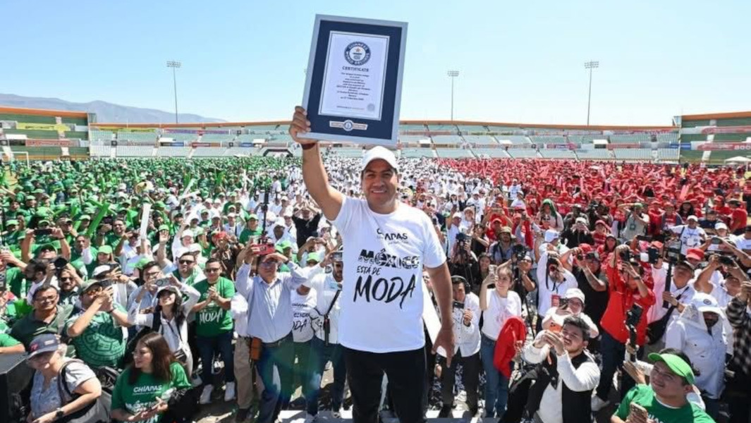 Man holding a GWR certificate in the air in front of a crowd of people in Mexico shirts