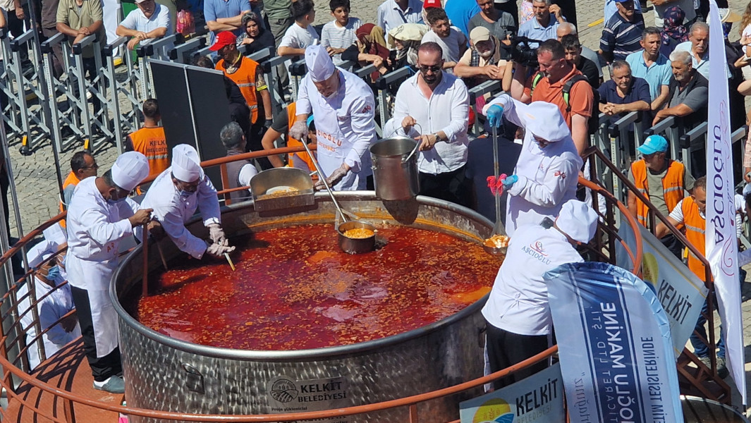 Chefs stirring the giant pot of baked beans in front of a crowd