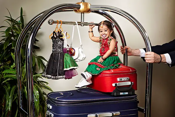 shortest woman living sitting on top of small suitcase